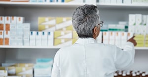 head of pharmacy woman looking at wall of medications