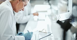 specialty pharma leader taking notes while looking at clinical trial data on computer